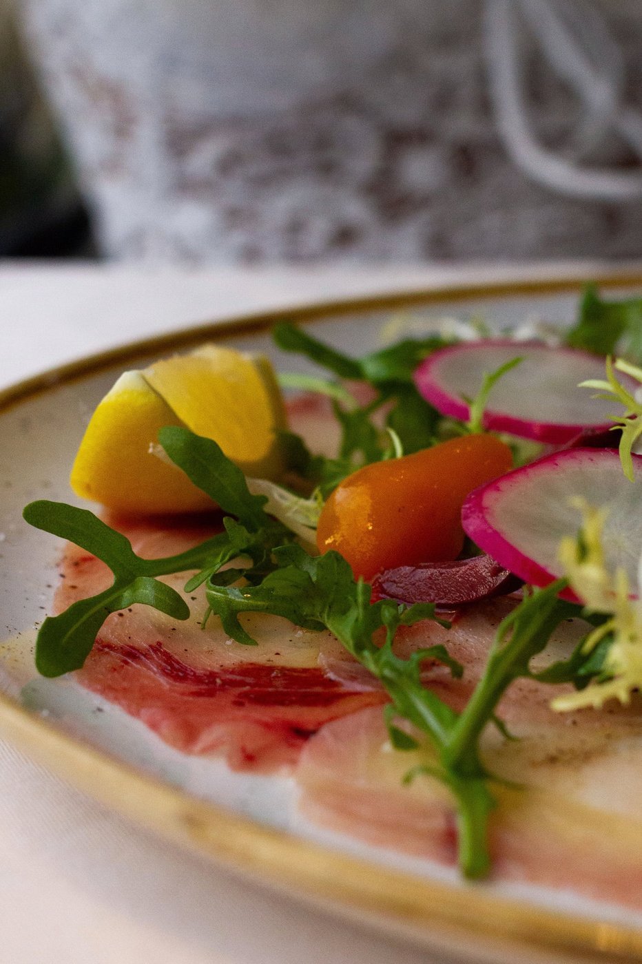Fish carpaccio with rocket, radish and cherry tomatoes